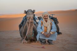 Moroccan Herder squatting in Sahara Desert