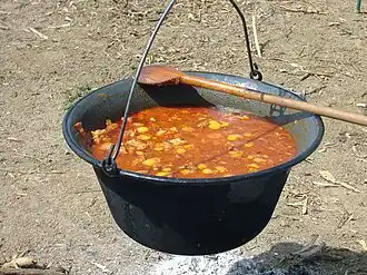 Goulash being cooked in a traditional cauldron called a bogrács