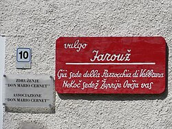 The Italian and Slovene sign says: "Farouž. Formerly the seat of the parish of Valbruna / Ovčja Vas."
